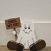 Hand-painted seated ghost holding a Smell My Feet sign