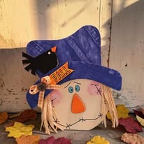 Handmade scarecrow shelf sitter with a purple hat and raffia hair